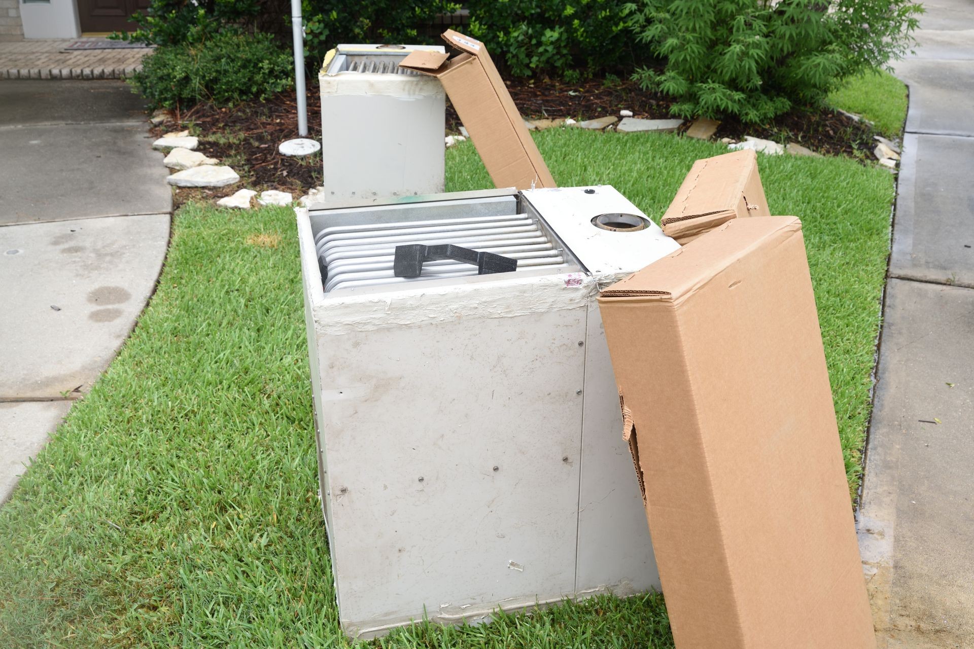 Old rusty gas furnace sitting by the curb with installation of new heating unit.